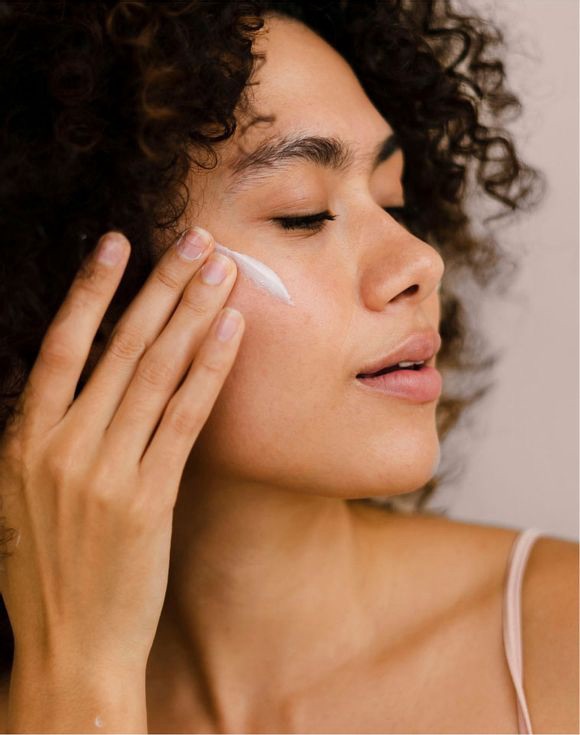Woman applying cream on her face. 
